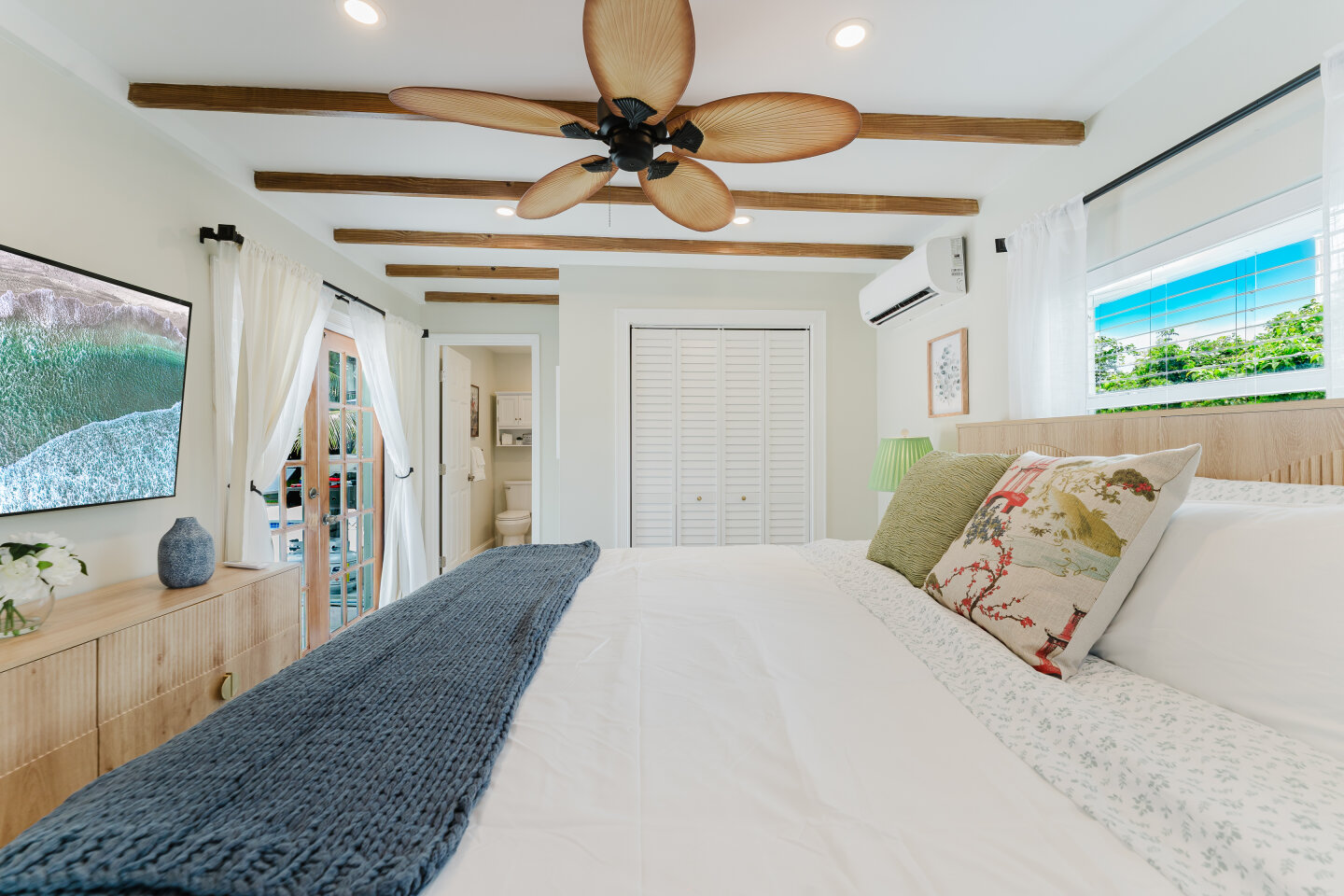 Bright primary bedroom with tropical ceiling fan