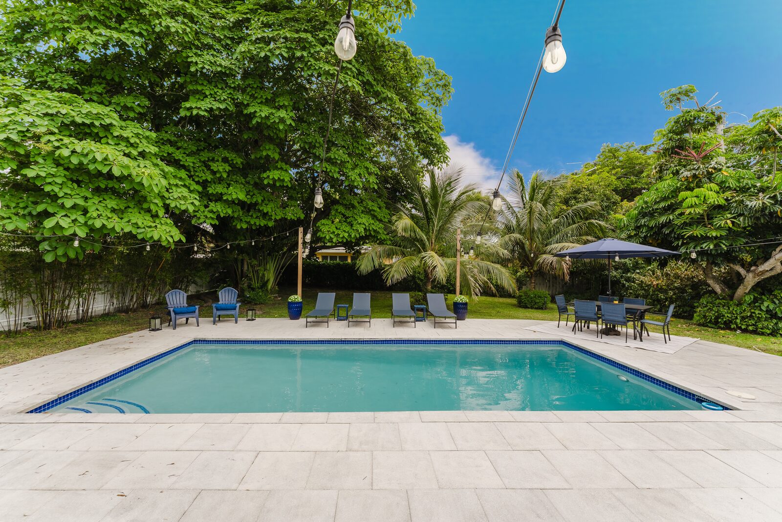 Private pool with lounge chairs and string lights